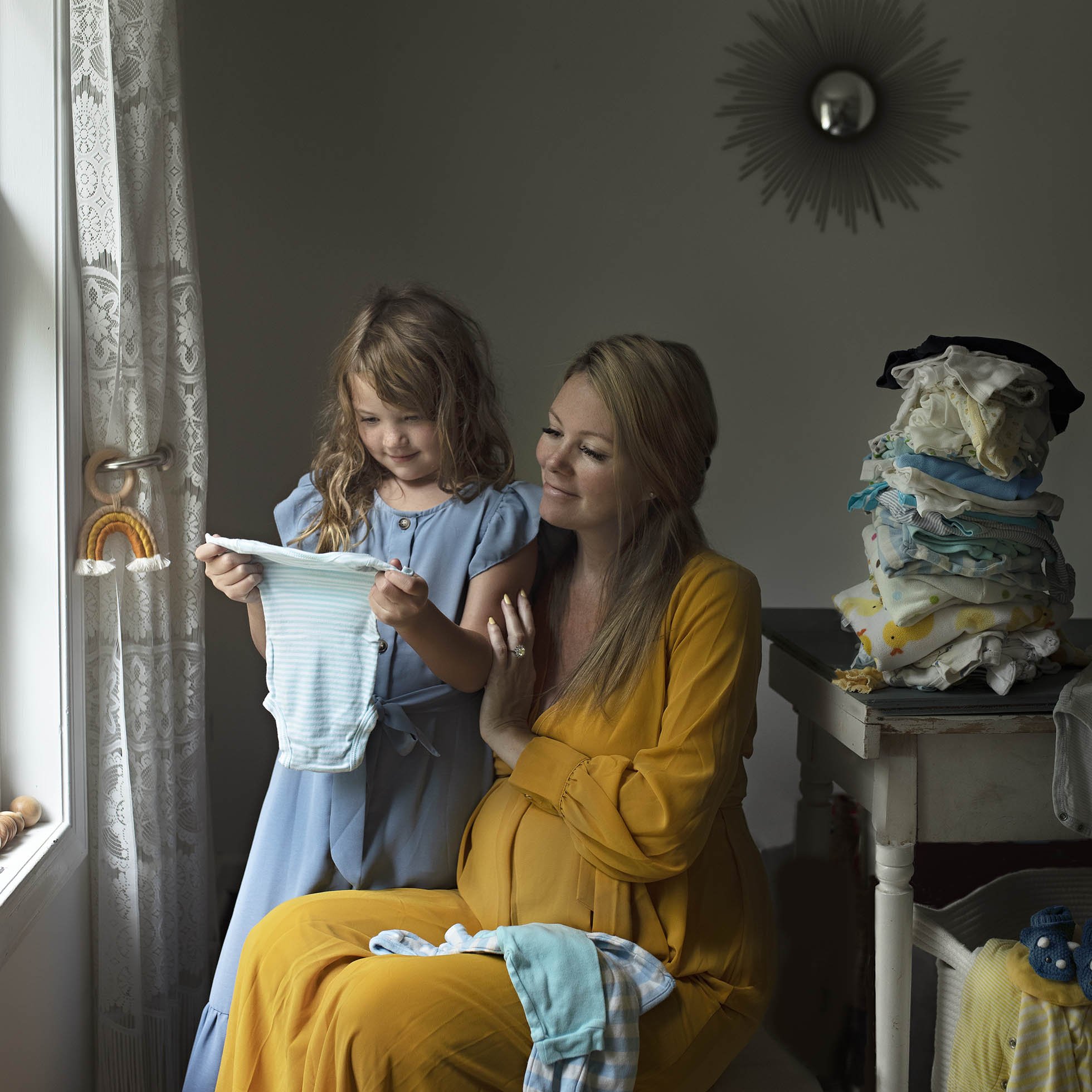 Portrait of mother folding baby clothes with older child