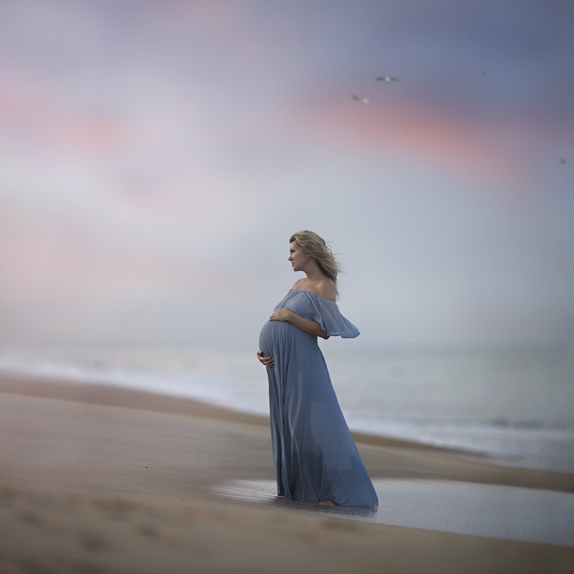 Pregnancy Self Portrait. Pregnant woman standing on the beach.