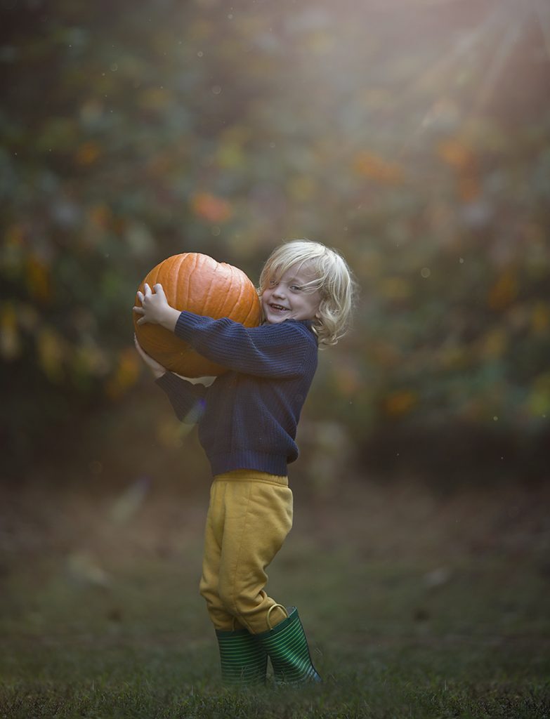 Little boy carrying a pumpkin. 