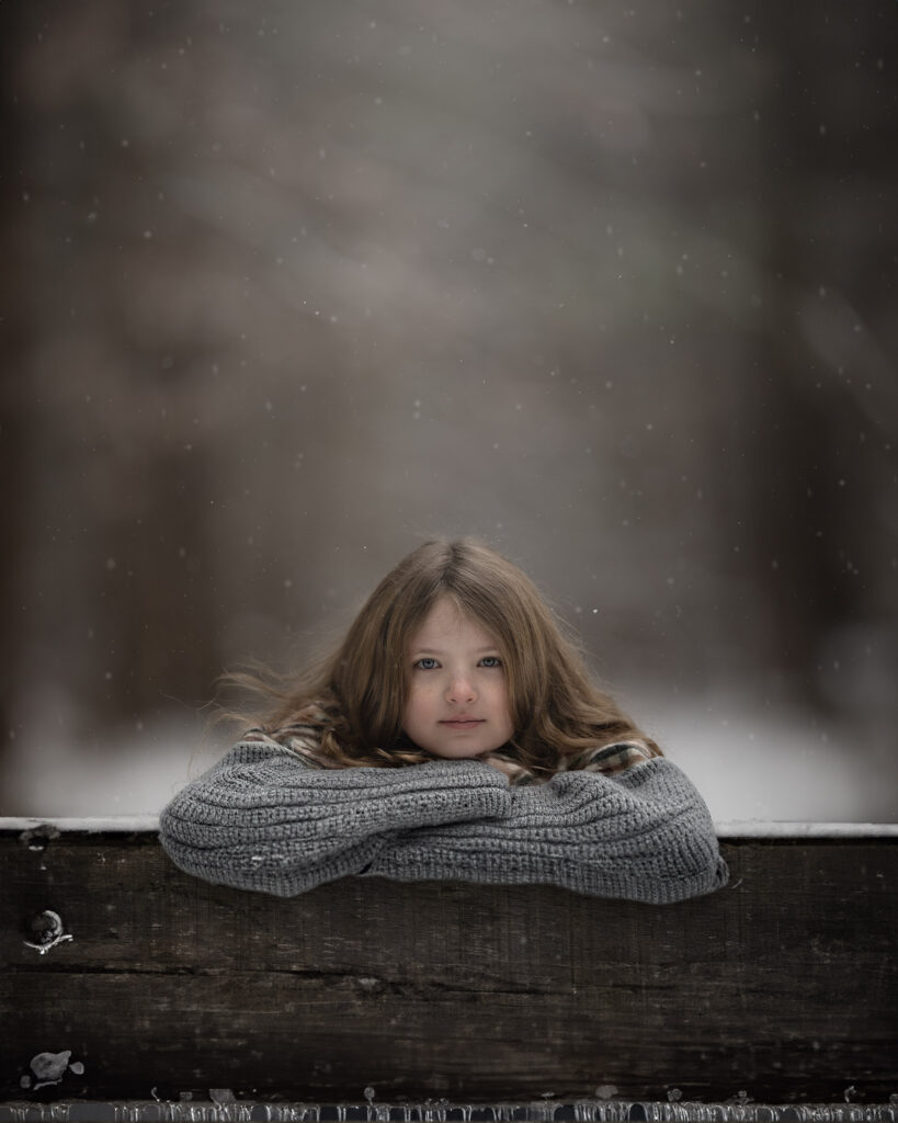 Winter Light Photography. Girl leaning on fence in snowy scene.